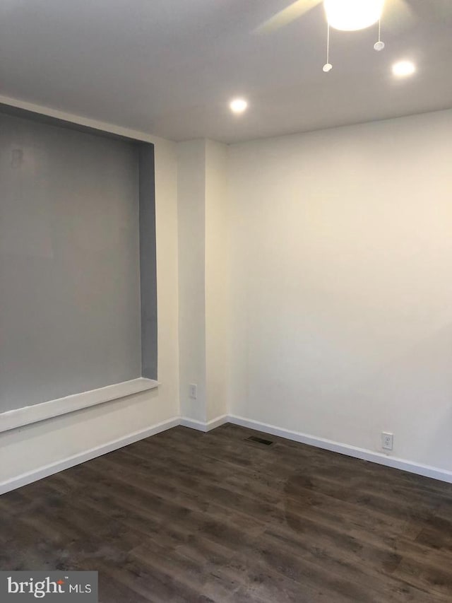 unfurnished room with ceiling fan and dark wood-type flooring