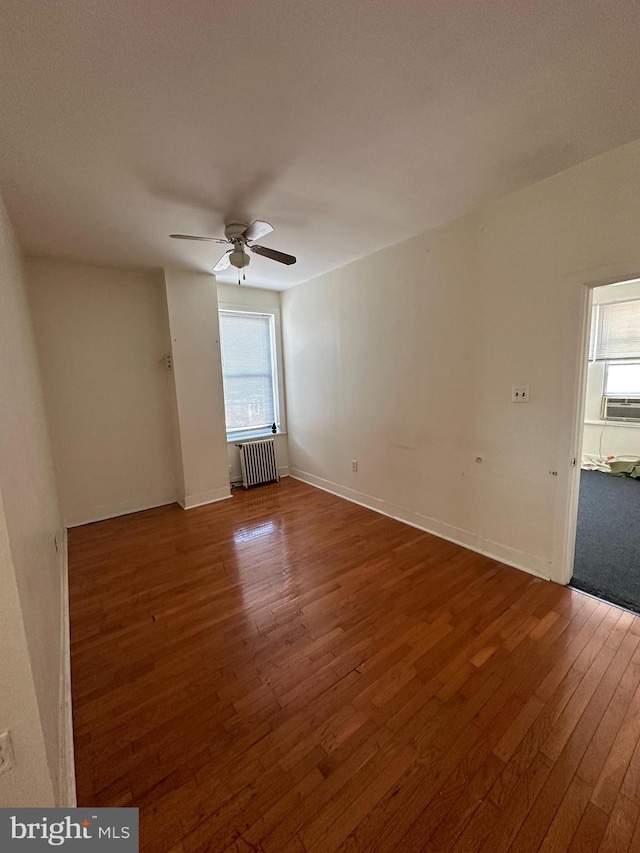 unfurnished room with radiator, ceiling fan, hardwood / wood-style floors, and cooling unit