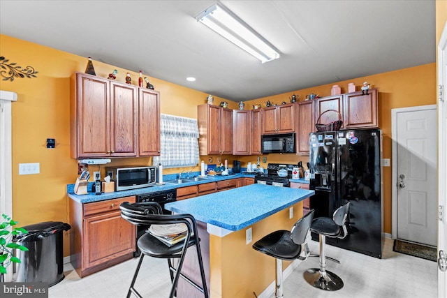 kitchen with a kitchen breakfast bar, a center island, black appliances, and sink