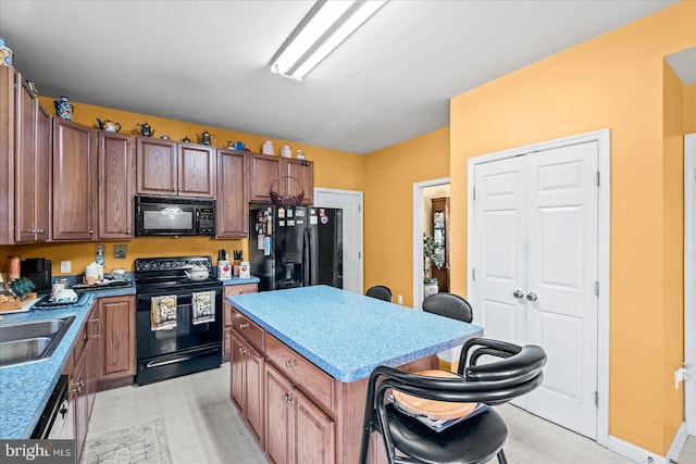 kitchen with a breakfast bar, a center island, sink, and black appliances