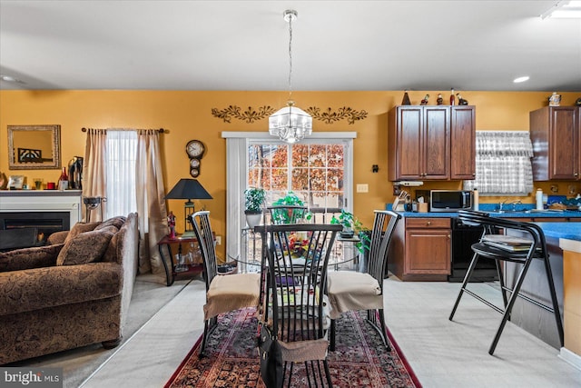 interior space with hanging light fixtures, black dishwasher, light colored carpet, and plenty of natural light