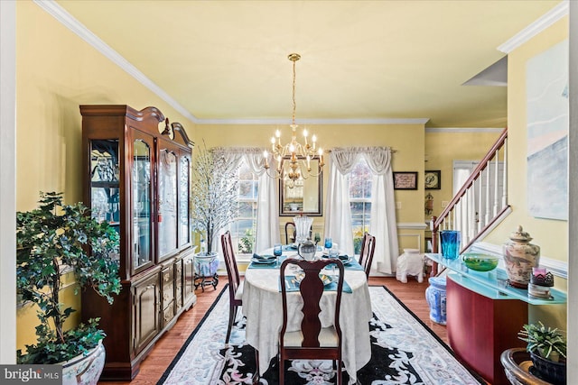 dining space featuring wood-type flooring, an inviting chandelier, and ornamental molding