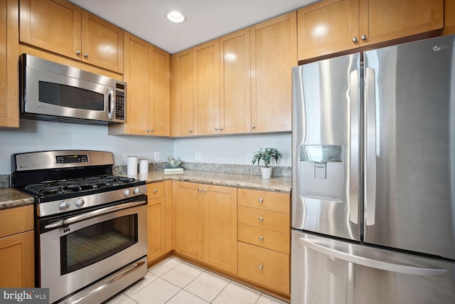 kitchen featuring light stone countertops, stainless steel appliances, and light tile patterned floors