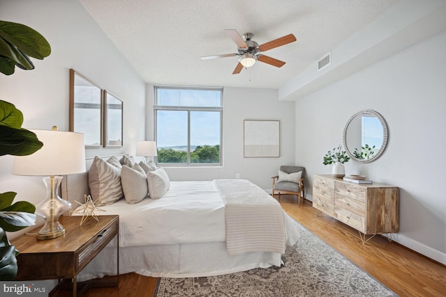 bedroom with ceiling fan, light hardwood / wood-style flooring, and a textured ceiling