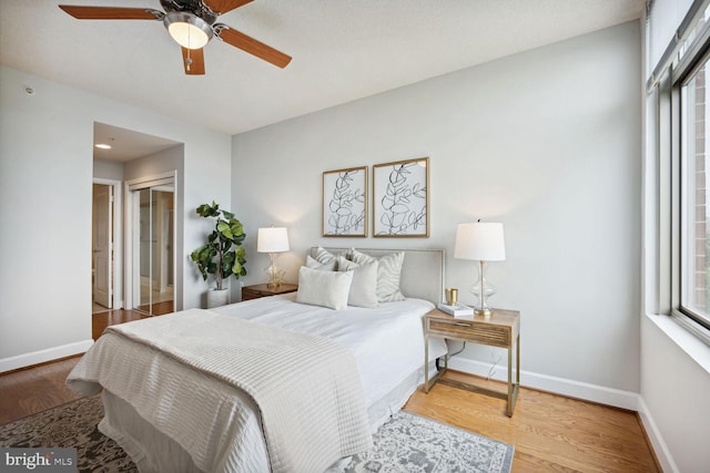 bedroom with multiple windows, ceiling fan, a closet, and hardwood / wood-style flooring