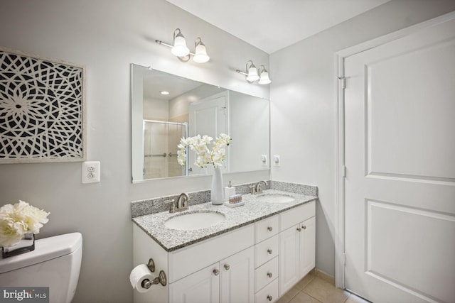 bathroom with toilet, vanity, tile patterned floors, and a shower with door