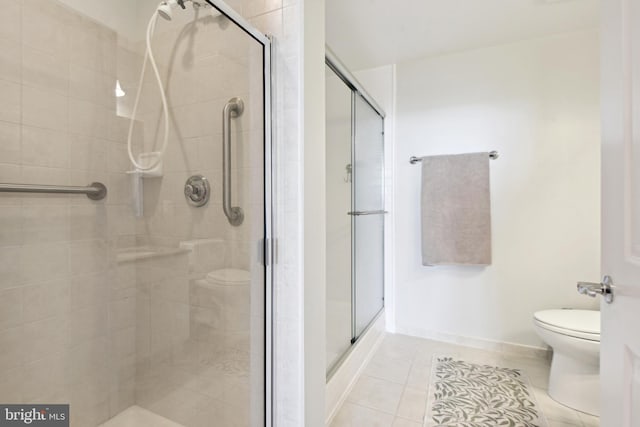 bathroom featuring tile patterned floors, toilet, and a shower with door