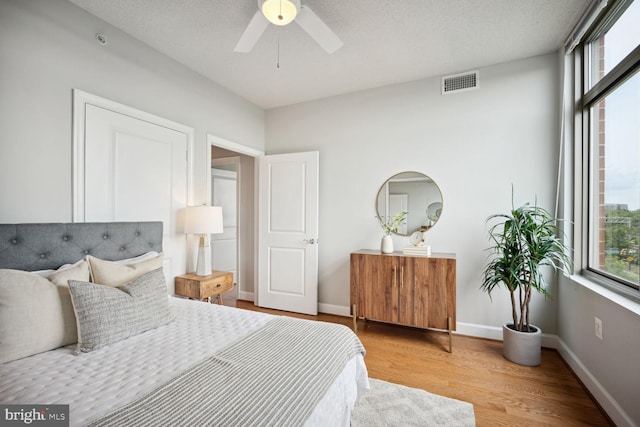 bedroom with ceiling fan, a textured ceiling, and light wood-type flooring