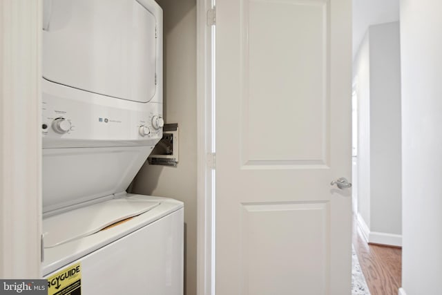 laundry room with stacked washer / drying machine and light hardwood / wood-style floors