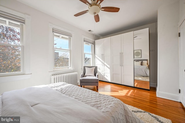 bedroom featuring ceiling fan, radiator, and light hardwood / wood-style flooring