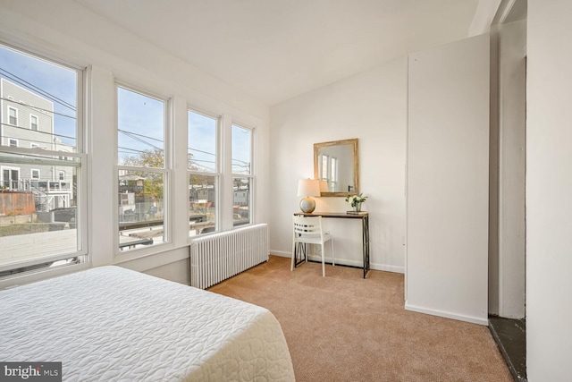 carpeted bedroom featuring multiple windows, radiator heating unit, and lofted ceiling