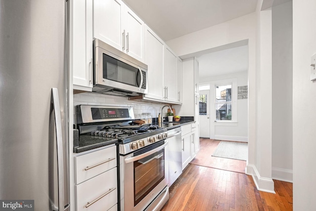 kitchen featuring hardwood / wood-style floors, backsplash, stainless steel appliances, and white cabinetry