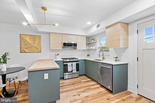 kitchen with plenty of natural light, sink, appliances with stainless steel finishes, and light hardwood / wood-style flooring