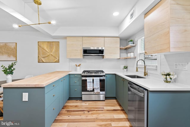 kitchen featuring backsplash, sink, light hardwood / wood-style flooring, blue cabinetry, and appliances with stainless steel finishes