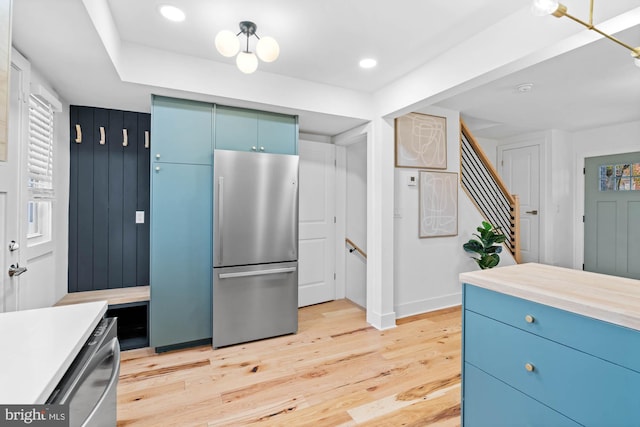 kitchen featuring light hardwood / wood-style flooring, blue cabinets, and appliances with stainless steel finishes