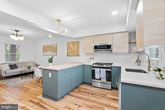 kitchen with a notable chandelier, stainless steel appliances, a wealth of natural light, and light hardwood / wood-style flooring