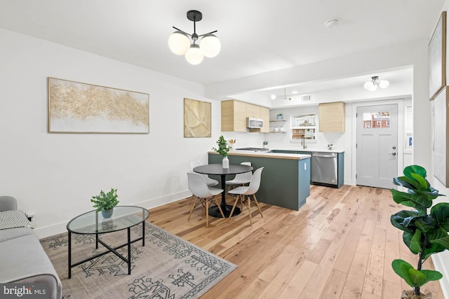 kitchen featuring dishwasher, light hardwood / wood-style flooring, kitchen peninsula, light brown cabinetry, and a breakfast bar