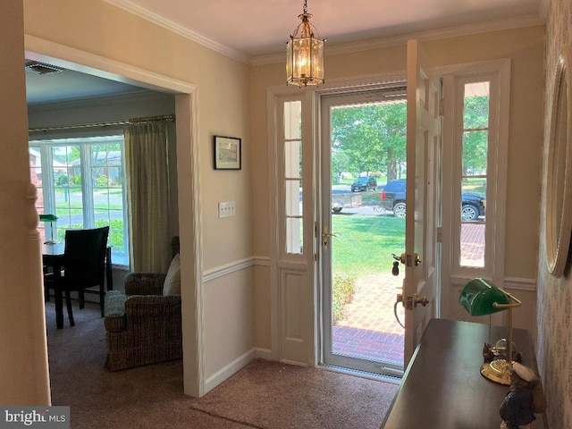 carpeted entryway with ornamental molding and a chandelier