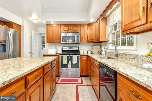 kitchen featuring light stone counters, sink, light tile patterned floors, and stainless steel appliances