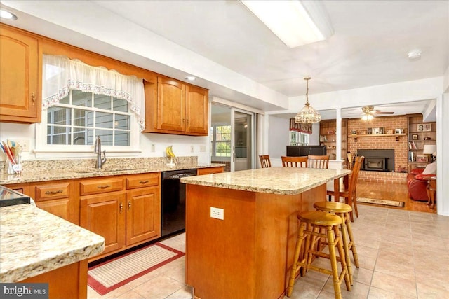 kitchen featuring a center island, a wood stove, sink, hanging light fixtures, and black dishwasher