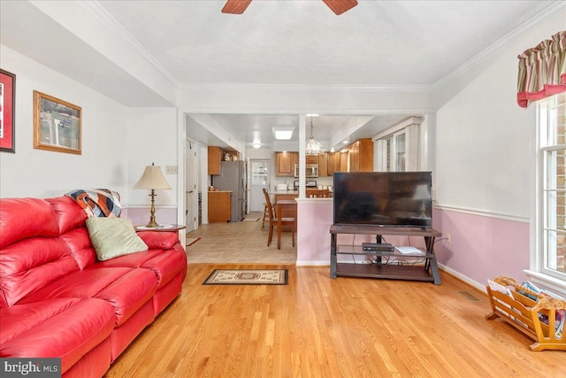 living room with ceiling fan, light hardwood / wood-style flooring, crown molding, and plenty of natural light