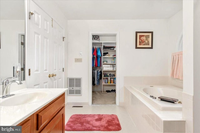 bathroom with tile patterned floors, vanity, and a relaxing tiled tub