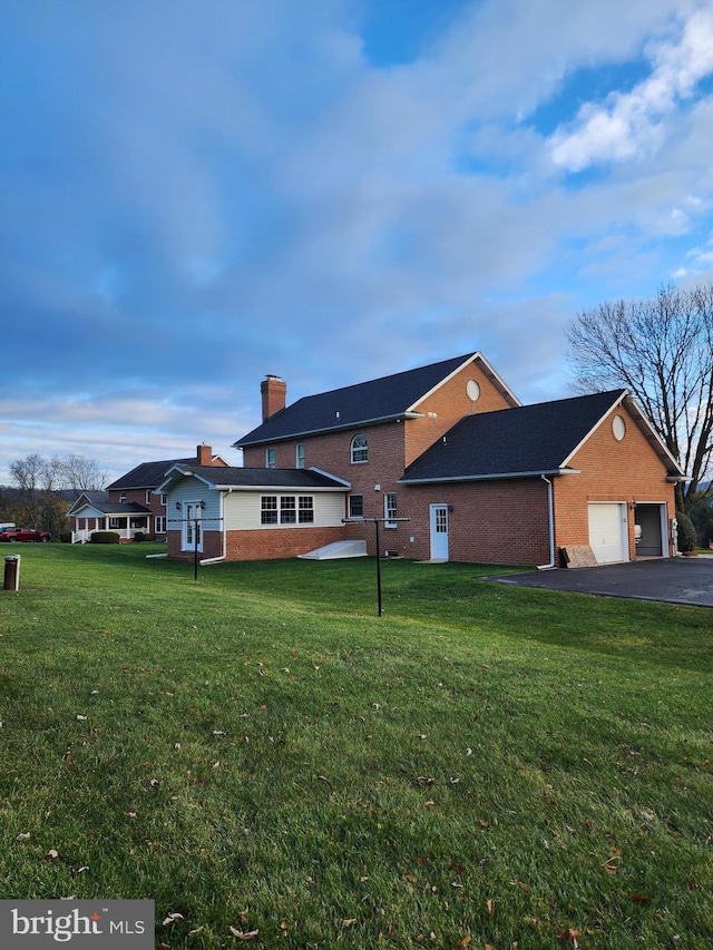 back of property with a lawn and a garage