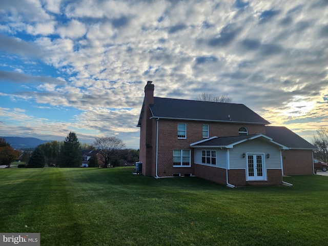 back house at dusk featuring a lawn