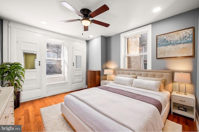 bedroom with ceiling fan, light hardwood / wood-style flooring, and multiple windows