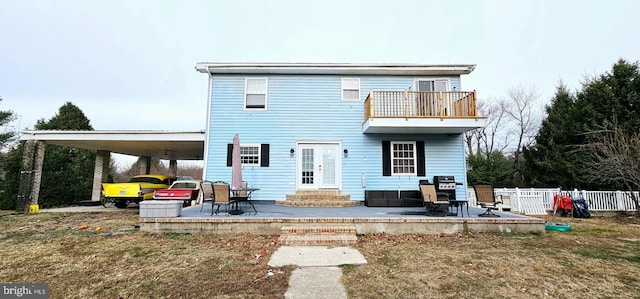 rear view of property featuring a lawn, a carport, a balcony, and a patio