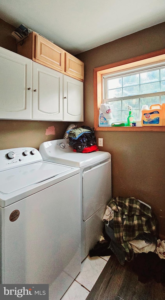 clothes washing area featuring washer and clothes dryer, cabinets, and light hardwood / wood-style floors