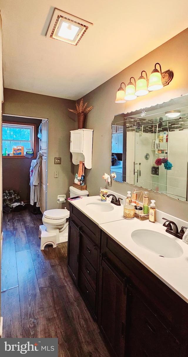 bathroom featuring hardwood / wood-style floors, vanity, toilet, and walk in shower