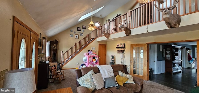 living room featuring a skylight, dark wood-type flooring, high vaulted ceiling, and an inviting chandelier