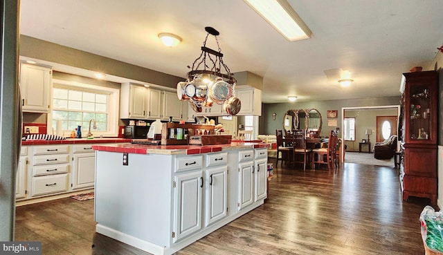 kitchen with white cabinets, a kitchen island, dark hardwood / wood-style flooring, and hanging light fixtures