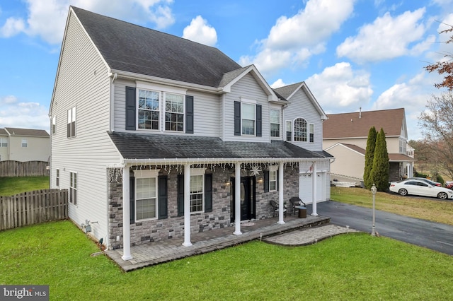 front of property featuring a garage, covered porch, and a front yard