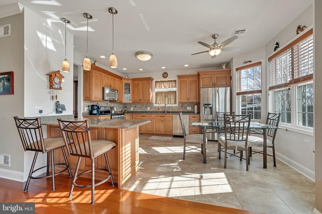 kitchen with light stone countertops, ceiling fan, stainless steel appliances, light hardwood / wood-style floors, and decorative backsplash