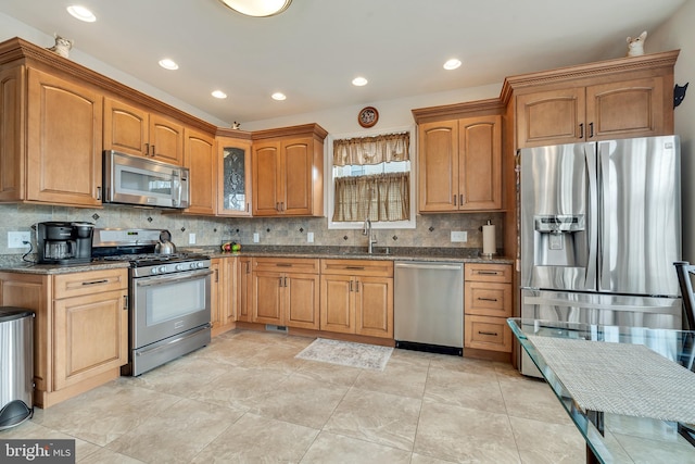 kitchen featuring decorative backsplash, appliances with stainless steel finishes, sink, light tile patterned floors, and stone countertops