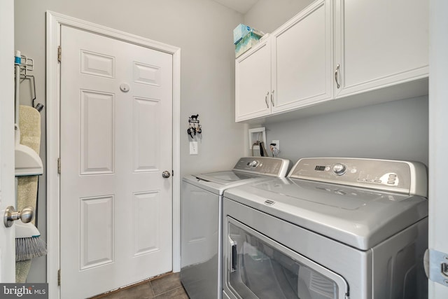 laundry room featuring cabinets, independent washer and dryer, and dark tile patterned flooring