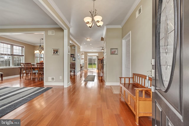 foyer with wood-type flooring, ceiling fan with notable chandelier, and crown molding