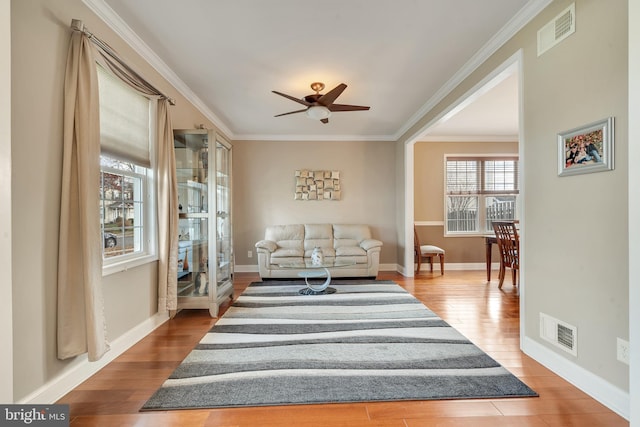 living area with hardwood / wood-style flooring, ceiling fan, and ornamental molding