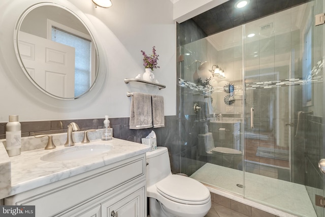 bathroom featuring vanity, a shower with shower door, tile walls, and toilet