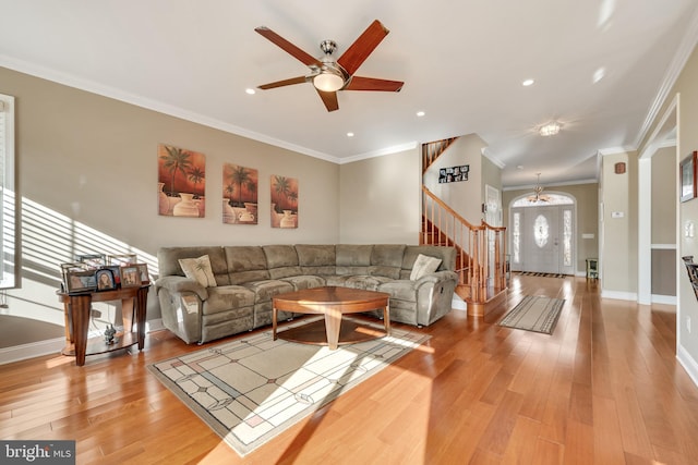 living room with light hardwood / wood-style flooring, ceiling fan with notable chandelier, and ornamental molding