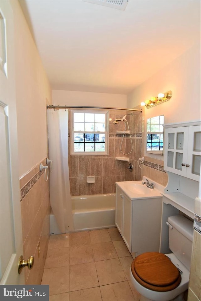 full bathroom featuring toilet, plenty of natural light, shower / tub combo with curtain, and tile patterned flooring