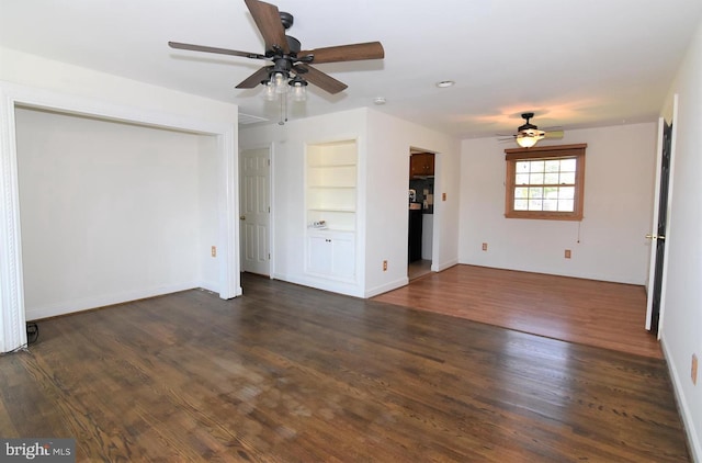 unfurnished living room featuring built in shelves, dark hardwood / wood-style flooring, and ceiling fan