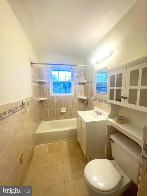 full bathroom with tile patterned floors, vanity, tile walls, toilet, and tiled shower / bath