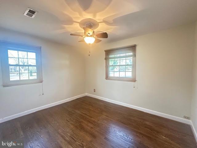 unfurnished room with ceiling fan and dark wood-type flooring