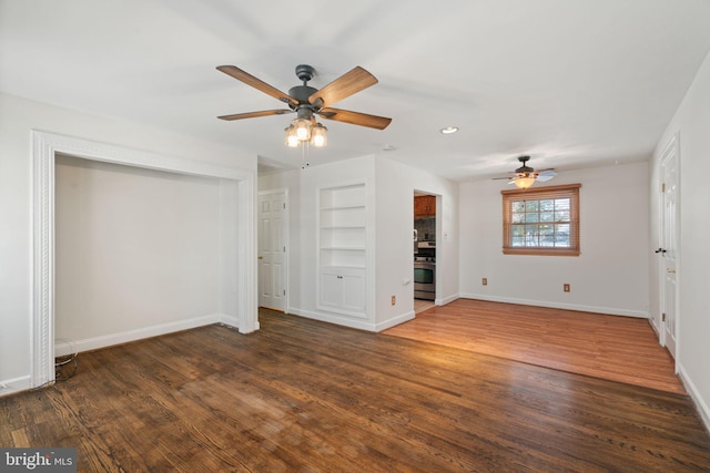 unfurnished living room with built in shelves, ceiling fan, and dark wood-type flooring