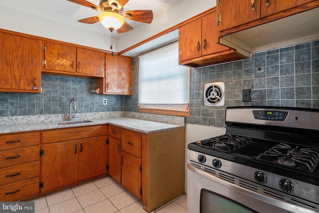 kitchen with ceiling fan, sink, stainless steel range with gas cooktop, backsplash, and light tile patterned flooring