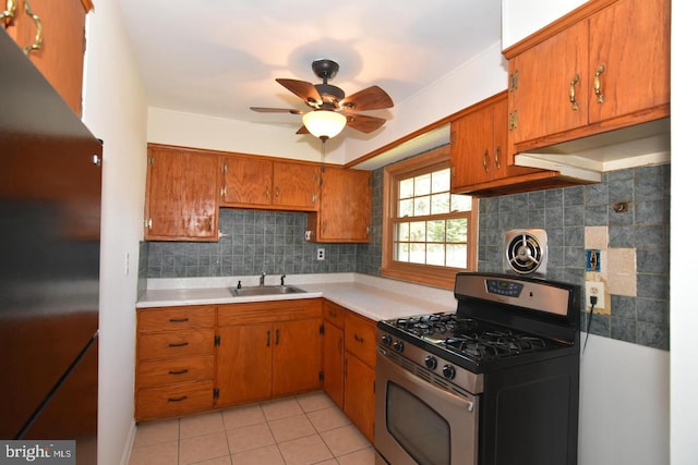 kitchen featuring refrigerator, gas stove, ceiling fan, sink, and light tile patterned flooring