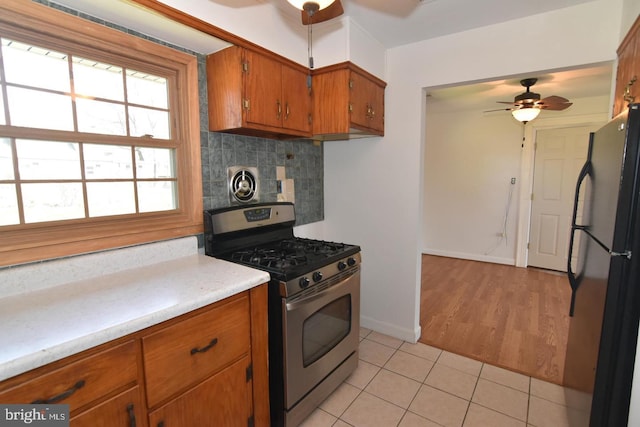 kitchen featuring ceiling fan, tasteful backsplash, stainless steel gas range oven, refrigerator, and light tile patterned flooring